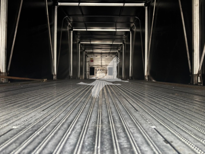 Flatbed trailer interior with metal ribbed floor and side rails, interior perspective view looking forward.