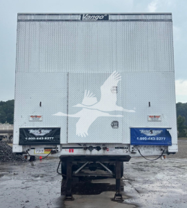 Rear view of a 2014 Mac aluminum flatbed trailer with a silver diamond plate rear doors, Kango logo at top center, two blue protective panels with white bird graphic, and registration/stock numbers visible.
