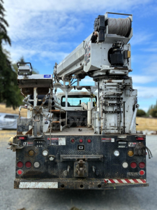 Rear view of a used 2007 International 7400 digger-derrick truck with crane and cable drum, showing bumper, lights, and equipment mount.