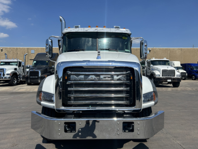 Mack GR64B front view showing large chrome grille and bumper, with other trucks in background.