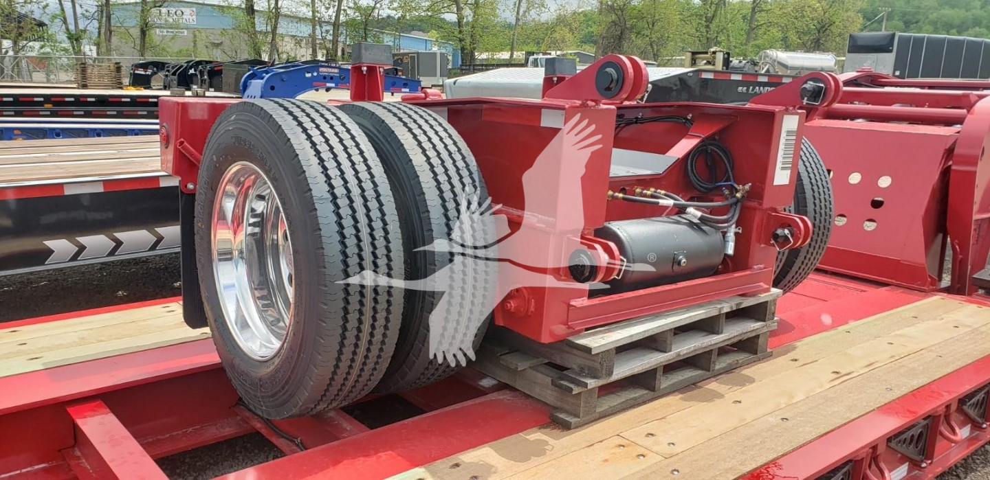 Twin-axle Fontaine flip axle assembly on a lowboy trailer showing red framework, dual tires, hydraulic components and mounting hardware.