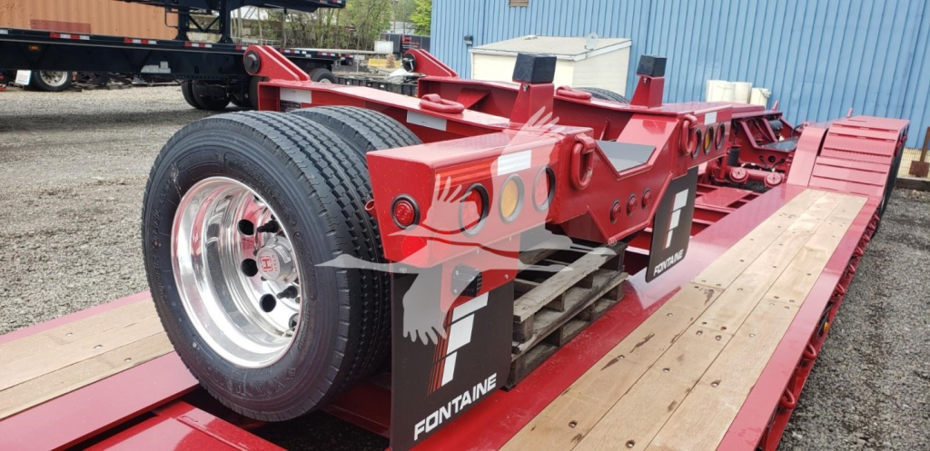 Fontaine flip axle trailer on a lowboy with a red frame, dual rear tires, and wooden deck showing Fontaine branding.