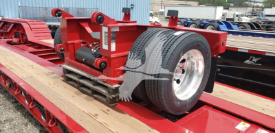 Fontaine flip axle trailer component on red lowboy with wheel and hydraulic mechanism visible
