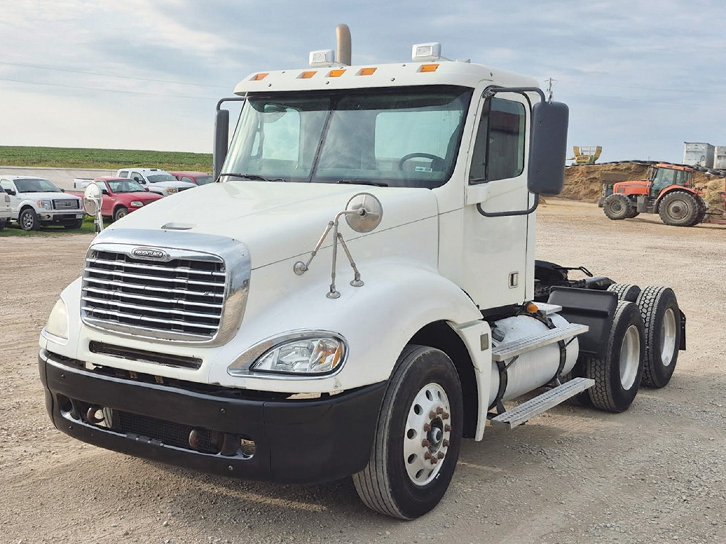 Truck cab interior not visible; Freightliner Columbia CL120 daycab with white exterior, front grille, headlights, dual rear wheels, and fuel tanks.