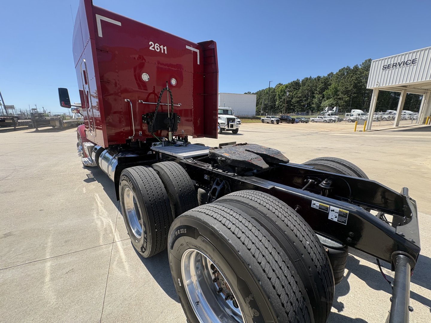Peterbilt 579 semi truck chassis rear view showing dual rear axles and red sleeper with white numbers '2611' on the cab side.
