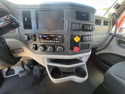 Truck dashboard view showing steering column, center console with radios and controls, climate dials, cup holders, and storage compartments.