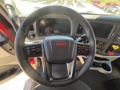 Peterbilt 579 dashboard and steering wheel view showing steering wheel with Peterbilt logo, digital gauge cluster, and control panels in the cab.