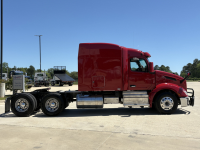Peterbilt 579 tractor sleeper cab side view showing red exterior and chrome fuel tanks.