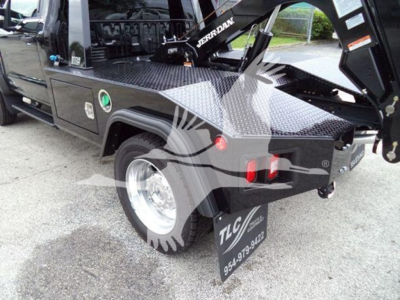 Ford F450 truck rear wheel area showing bed toolbox and tow hitch with winch equipment mounted, TLC branding on mudflap and side step text