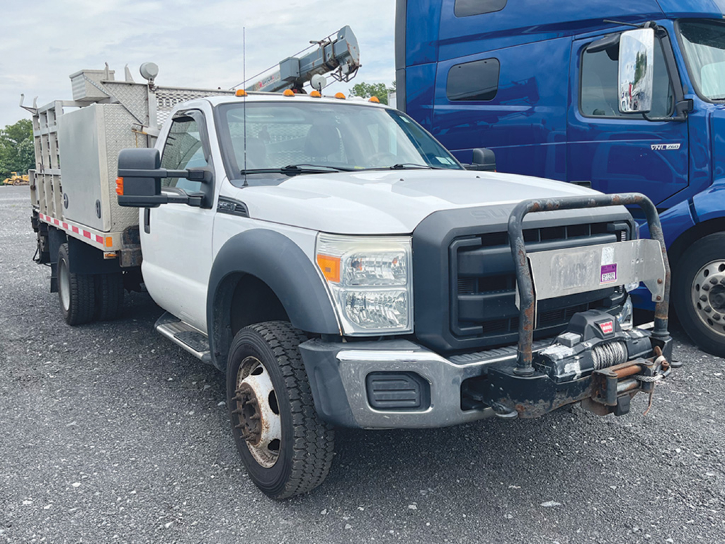 2016 Ford F-550 dually service truck with utility bed and front brush guard, viewed from front-left, showing large bumper, winch, and dual rear wheels.