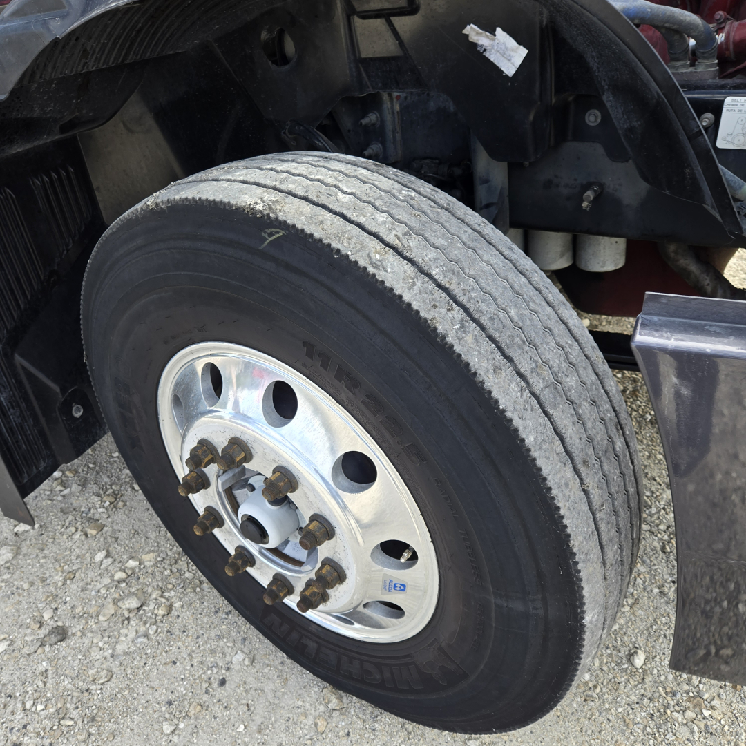 Front wheel and dual rear axle area of a 2019 Mack ANTHEM day cab truck showing a large treaded tire, metal lug nuts, and wheel hub.