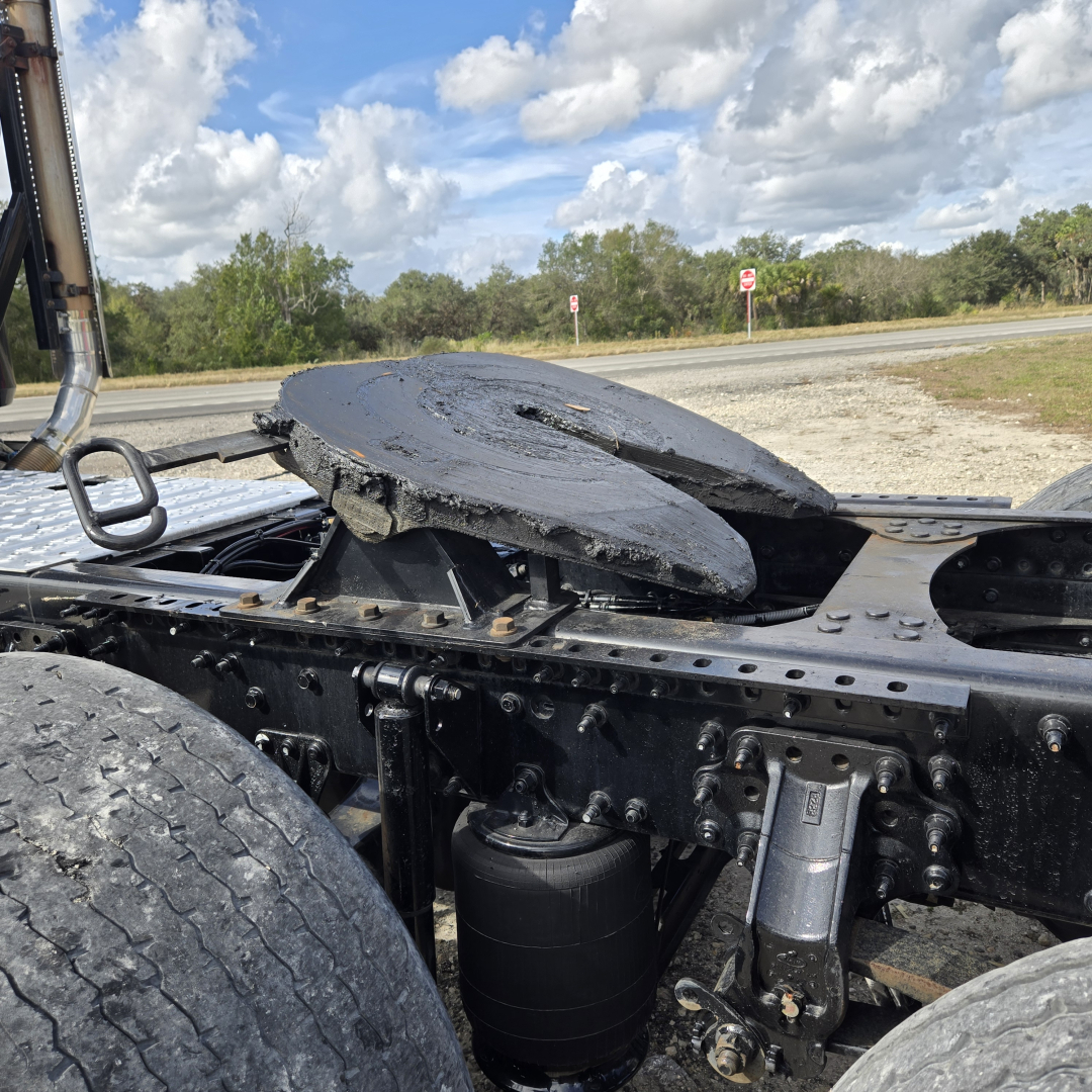 Chassis of a used 2019 Mack day cab tractor showing a damaged circular fifth wheel and surrounding frame with hydraulic components and suspension.
