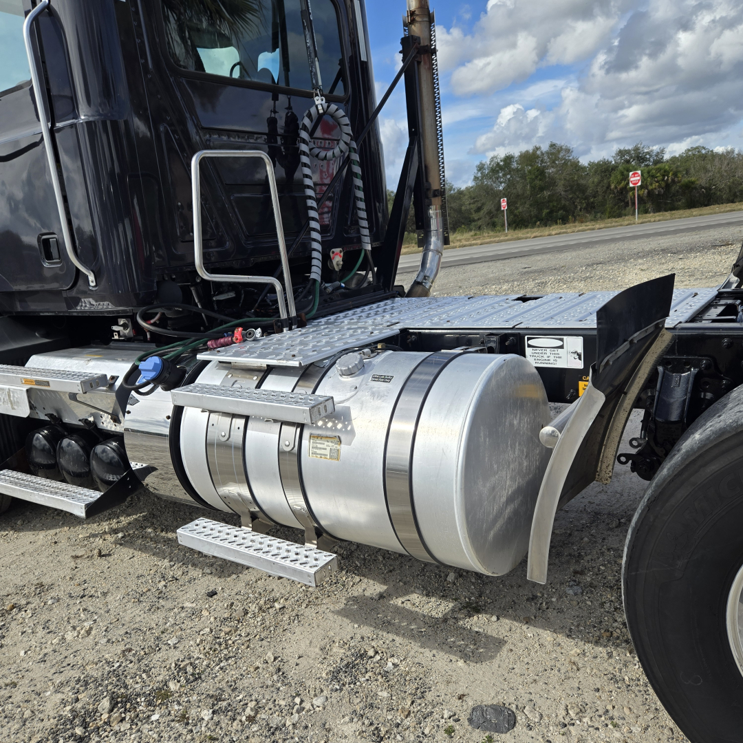Trailer-tractor fuel tank and side view of Mack ANTHEN day cab truck showing cylindrical aluminum fuel tank, steps, and chassis with hoses.