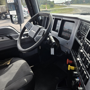 Truck cab interior showing steering wheel, dashboard, and control switches in a Mack ANTHEM day cab.