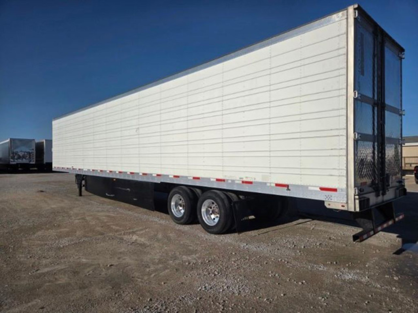 2019 Utility Reefer trailer with white panel sides, tandem axles, rear doors, and black undercarriage. No visible branding on side; basic aluminum paneling and reflective tape along lower edge.
