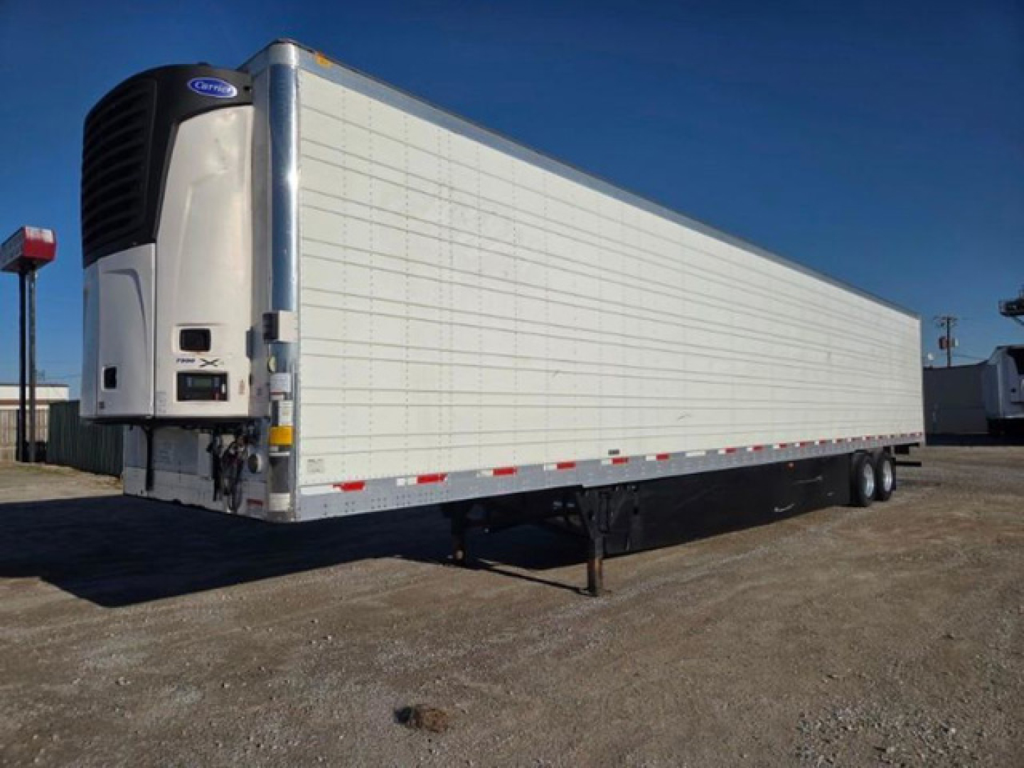 Utility reefer trailer with a large white refrigerated box and black refrigeration unit at the front showing a Thermo King/Carrier unit.