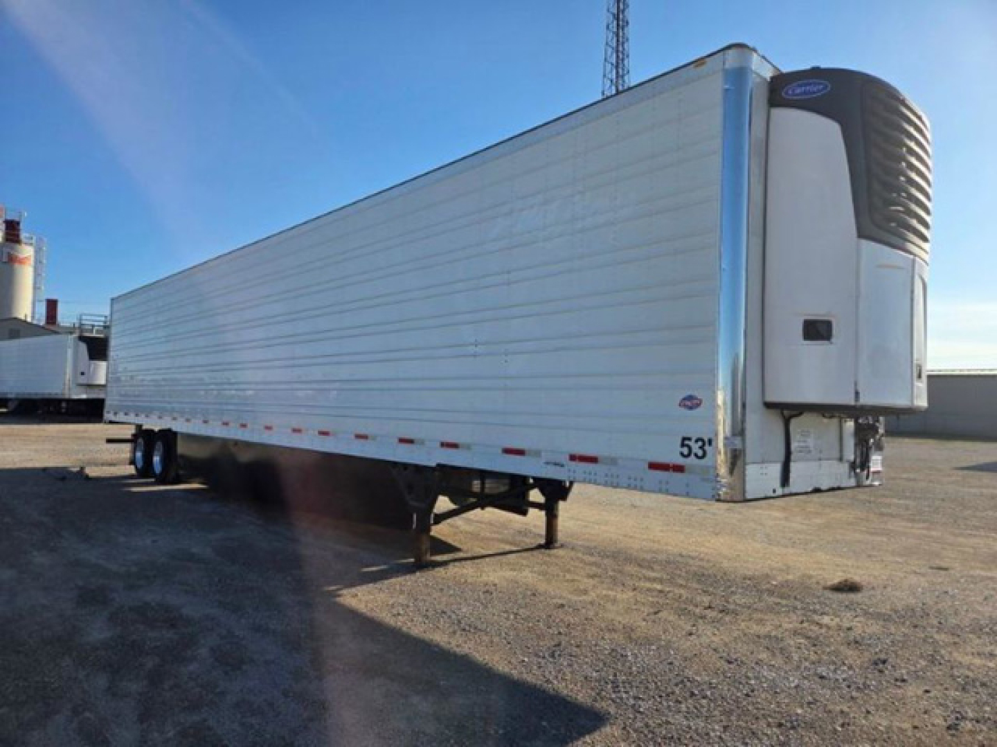 Utility reefer trailer in side view showing refrigerated unit at front, white corrugated side panels, drop legs under trailer, 53 foot length label near nose.