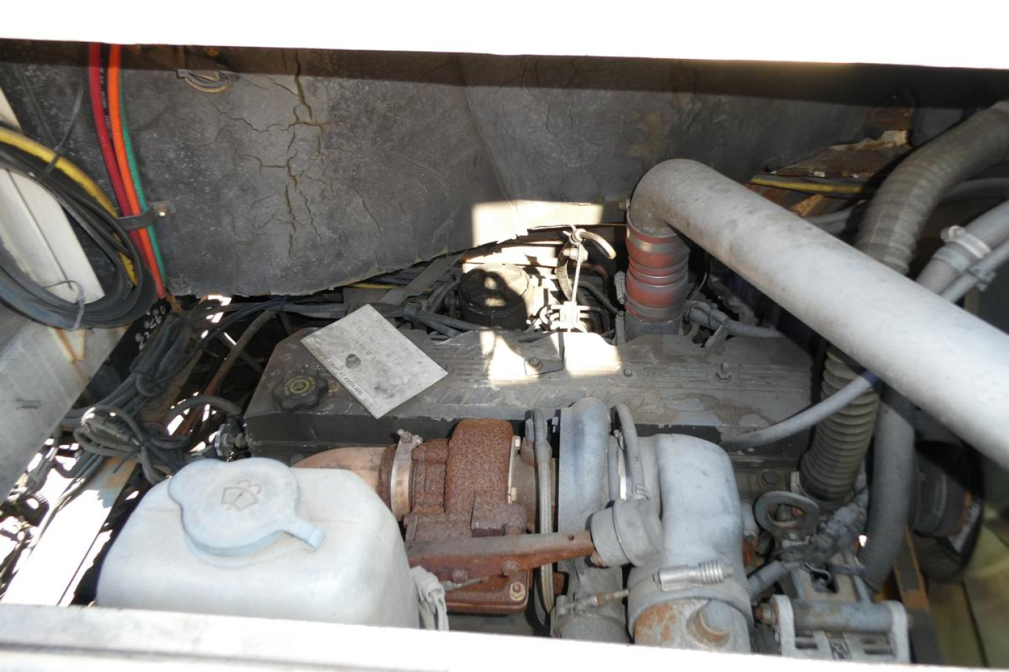 Engine bay of a 2000 Ottawa 30 truck showing coolant reservoir, turbocharger, hoses, and intake plumbing.