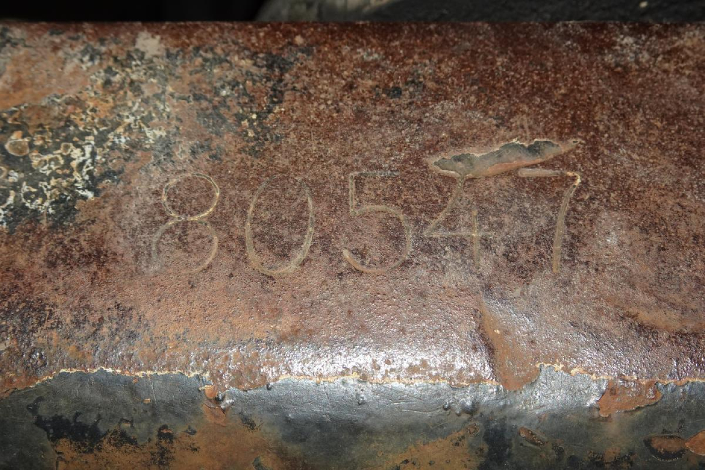Rusted metal surface with faded handwritten numbers 80547 and rough texture.