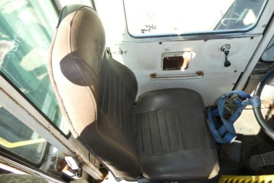 Seat and interior of a used 2000 Ottawa 30 yard truck cab showing brown driver seat, steering wheel, and door with metal latch.