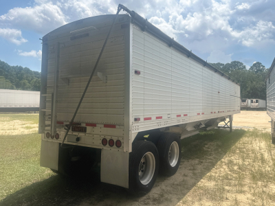 Rear/side view of a white 2020 Timpte Super Hopper trailer showing triple-axle undercarriage, side panel text not fully legible, rear doors, hinges, and ladders.