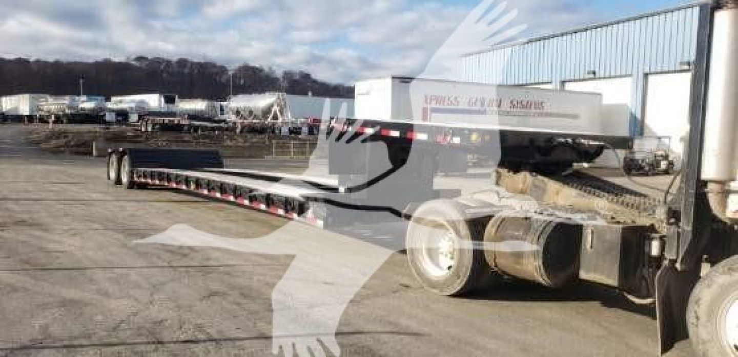 Trailer in a yard with long lowboy trailer and 80HDGS markings visible, equipment tires, and truck cab hitch area in view.