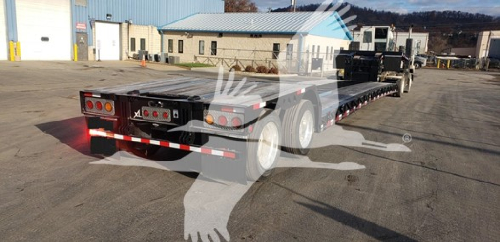 Lowboy trailer showing rear and side with dual tandem axles and ramps.