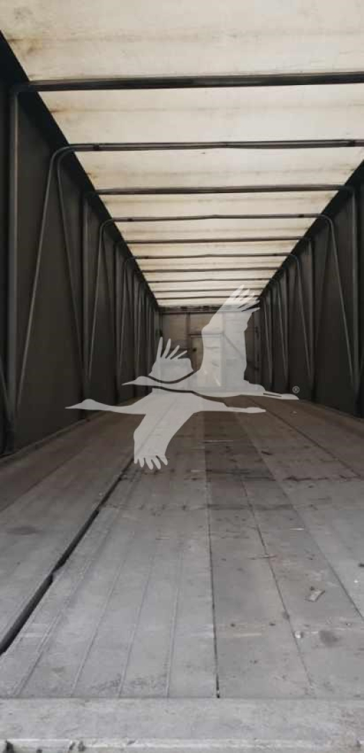 Interior view of a Benson flatbed trailer trailer bed with rails, empty and well-lit, no loads.
