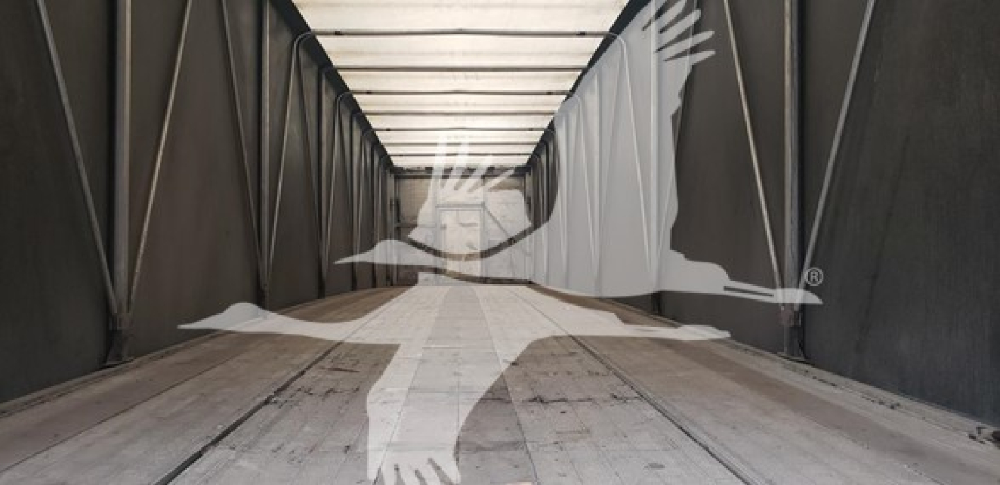 Trailer interior showing empty flatbed trailer with wooden floor and dark side walls, no payload visible.
