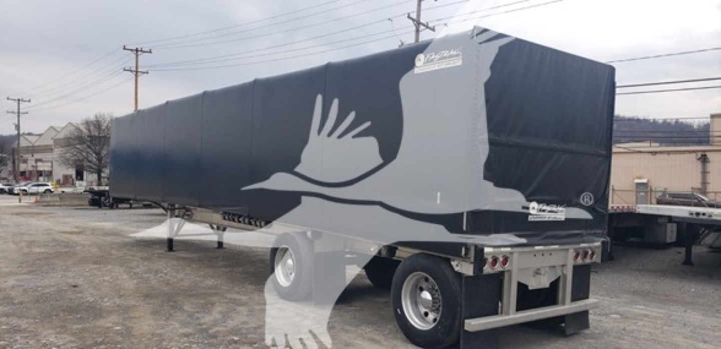 Trailer side view showing a Benson aluminum flatbed curtainside with a large white bird graphic on dark blue sides and a logo near the front, dual rear wheels, and a sturdy butler-style rear hitch.