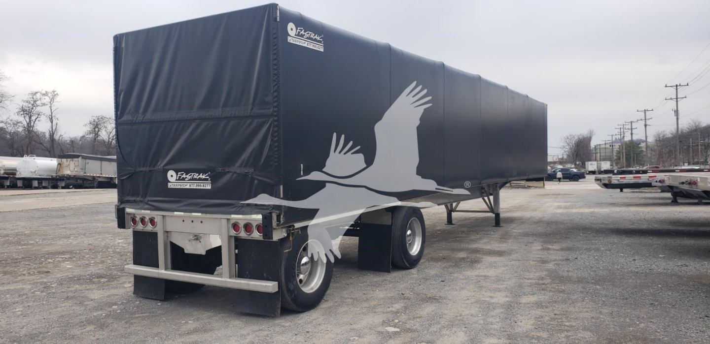 Trailer rear and side view of a Benson curtainside flatbed trailer with black tarp and white bird logo. Text on rear bumper area and side corner reads Benson trailers and warning labels.