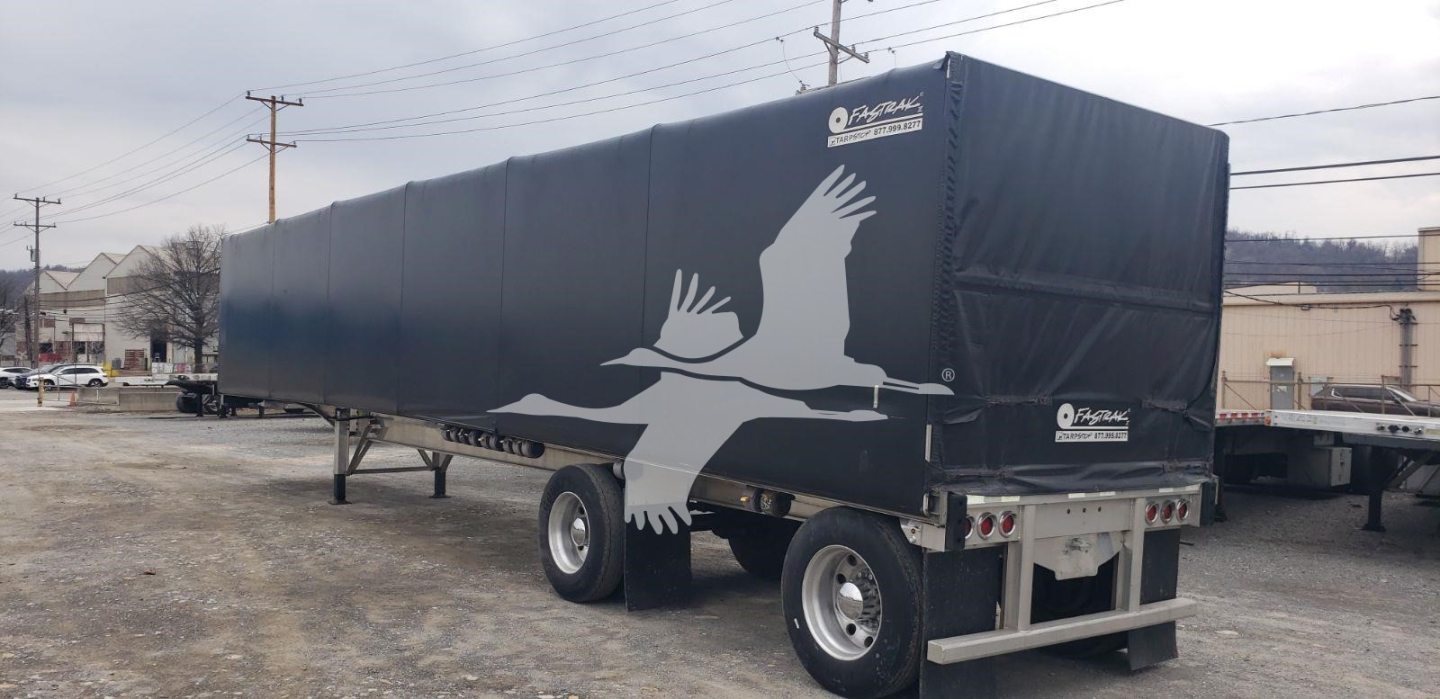 Trailer side with Benson logo and graphic of birds, black curtain-side flatbed trailer, dual wheels, rear ramps. No visible text other than Benson logo on tarpaulin.