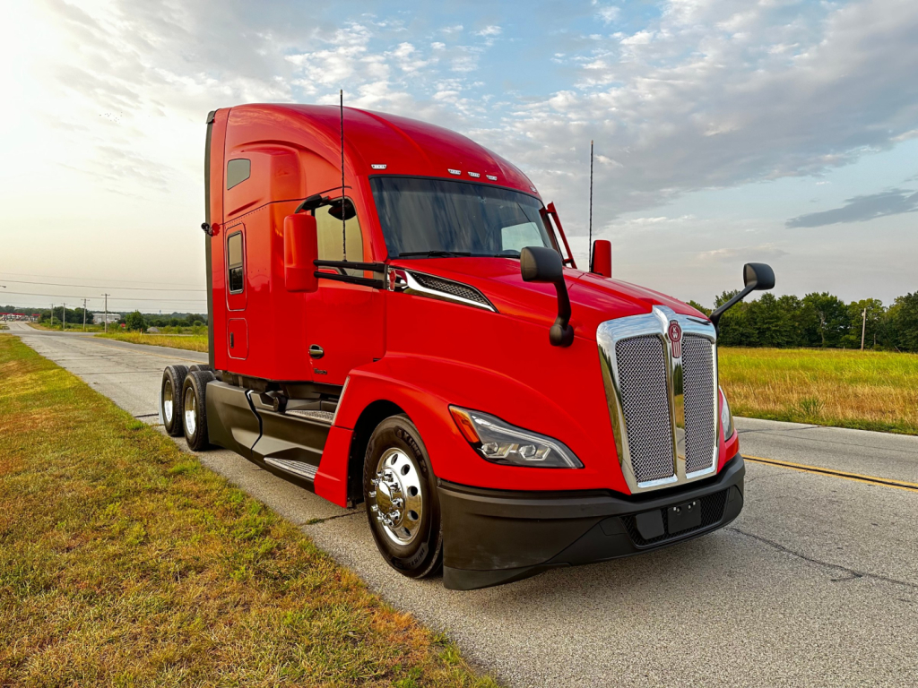 Kenworth T680 truck in red color parked on road showing front grille and left side view.