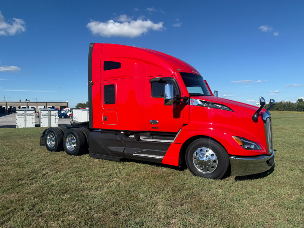 Kenworth T680 semi-truck with bright red exterior, sleeper cab, black lower trim, chrome wheels, and triple rear axles visible.