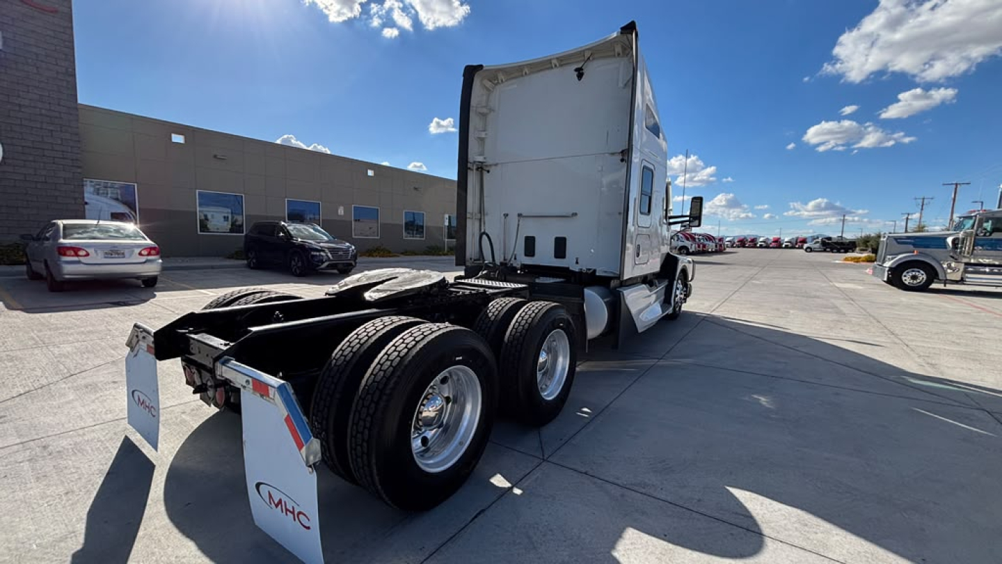 Kenworth T680 tractor back view showing rear axle with dual tires and fifth wheel, white cab, no trailer, daytime outdoor lot.