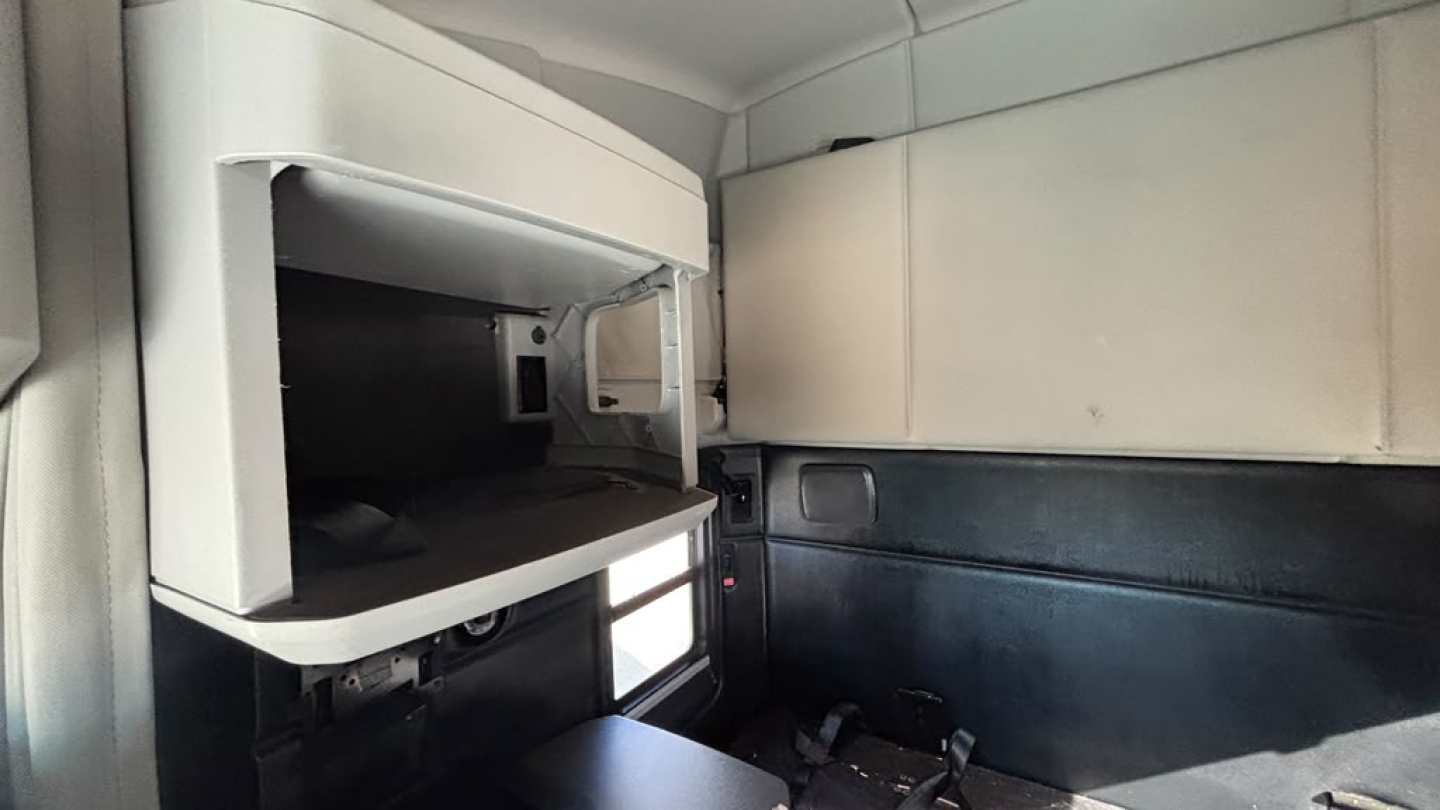 Kenworth T680 cab interior showing sleeper area with storage shelf and window inview
