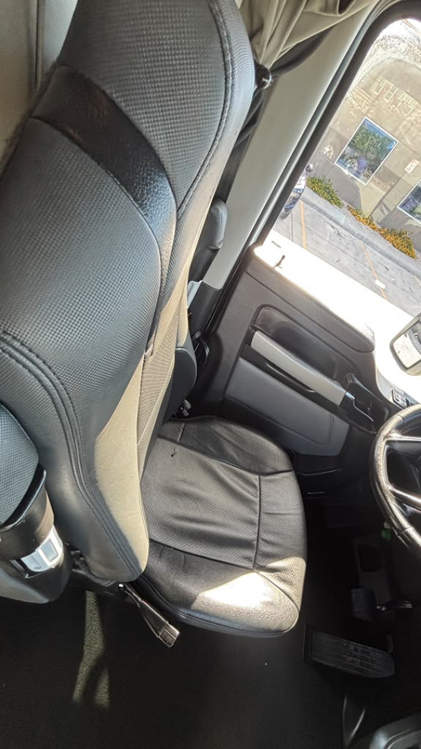 Kenworth T680 interior view of the driver seat and door panel; front cabin area visible with steering wheel and seat.