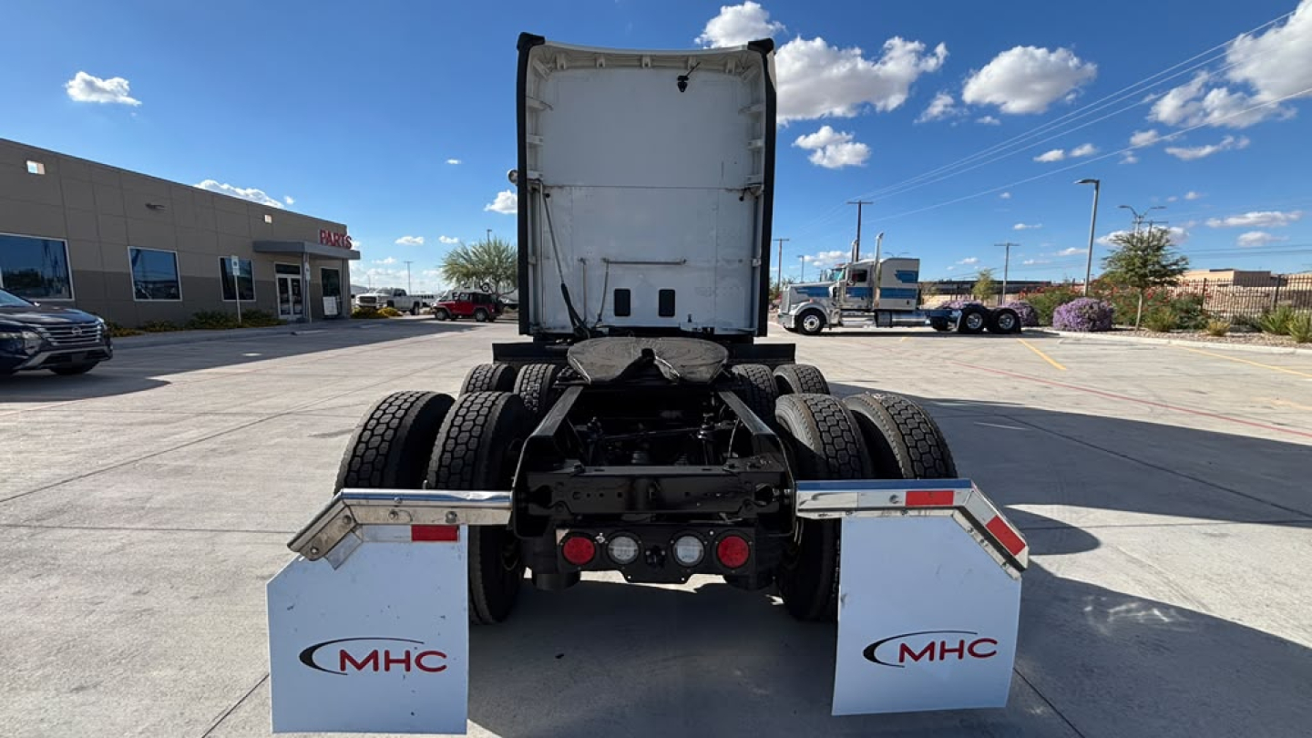 Kenworth T680 rear view showing fifth wheel, dual rear axles, and MHC logos on rear mud flaps.