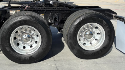 Dual rear wheels on a Kenworth truck chassis showing chrome rims and tires with visible frame and suspension components.