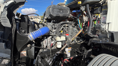 Kenworth T680 engine bay showing air intake, hoses, wiring harness, and turbocharger components.