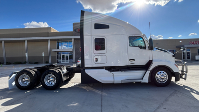 Kenworth T680 tractor cab side view showing front wheels and sleeper with white paint and black trim.