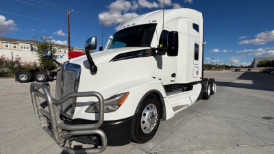 Kenworth T680 white sleeper tractor in a parking lot, front-left angle, with chrome bumper guard and large grille.
