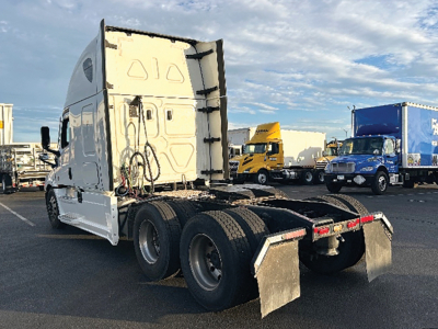 Freightliner Cascadia126 tractor rear view showing fifth wheel, dual rear axles, mudflaps, and chrome fuel tanks.