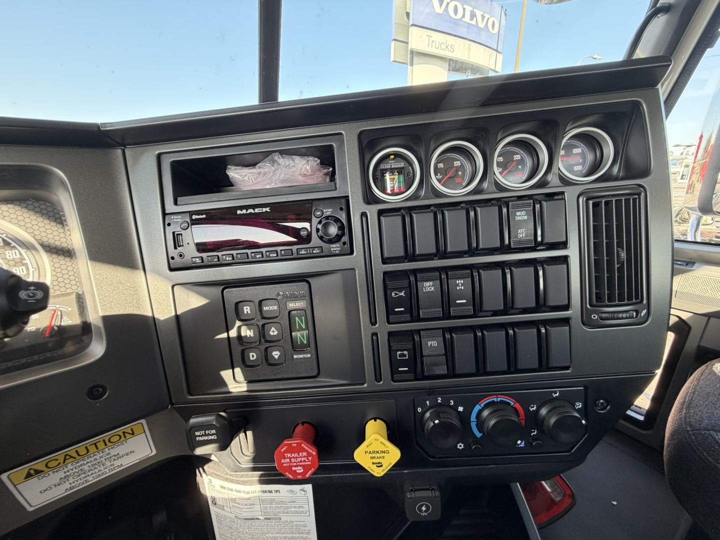 Dashboard view of a 2026 Mack GR64B rolloff truck showing instrument cluster, various switches, ignition, and climate controls.