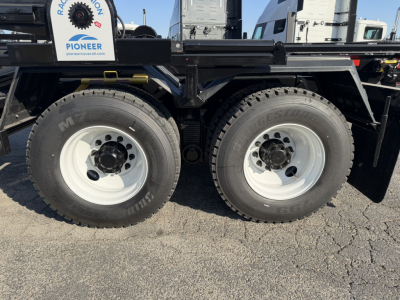 Mack GR64B chassis showing dual rear axles with large off-road tires and white steel wheels.