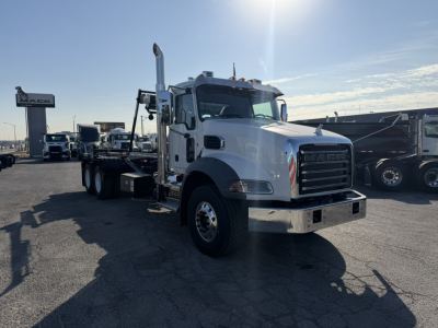 Mack GR64B roll-off truck in front view showing chrome bumper, large grille, tall exhaust stacks, and flatbed with wheel-lift.