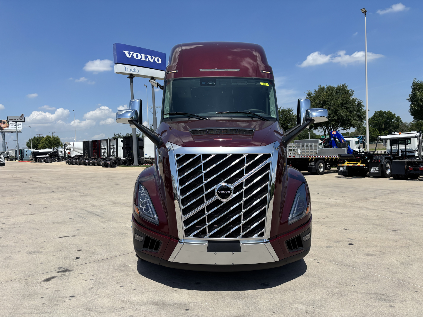 Volvo VNL truck front view showing large chrome grille, headlights, burgundy cab, and side mirrors.