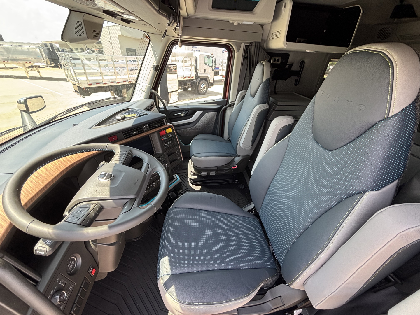 Volvo truck cab interior showing steering wheel, bucket seats, and dashboard with control panels.