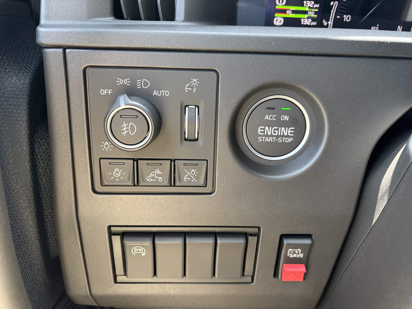 Volvo VNL64T860 dashboard with ignition engine start-stop button and lighting controls panel showing circular knob, switches, and red hazard button.