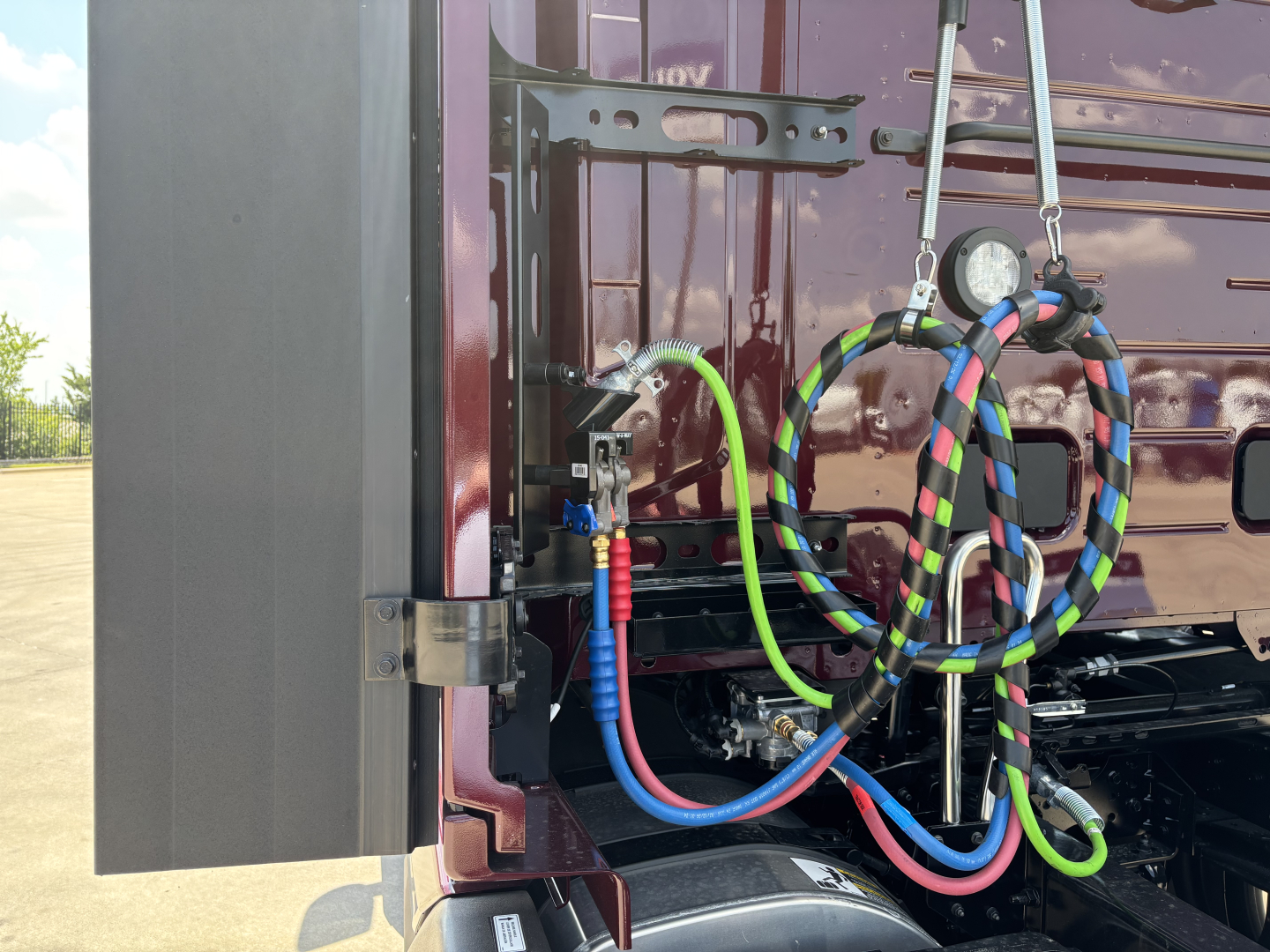 Volvo VNL64T860 engine bay area with multiple color-coded hoses (blue, red, green, black) and electrical connections; reservoir/valve components visible.
